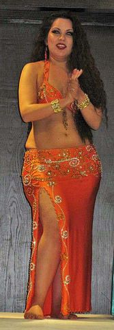 Claudia Leal viste conjunto naranja con oro